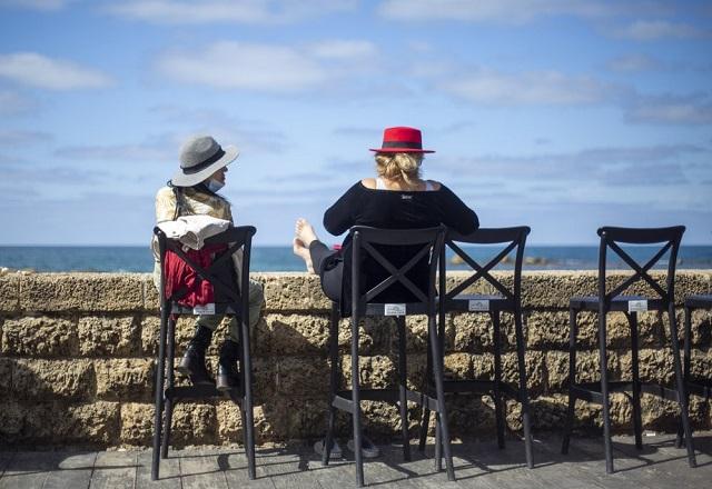 Sentadas em cadeiras, mulheres conversam e observam o mar em Tel Aviv, Israel (Ariel Schalit/AP News)
