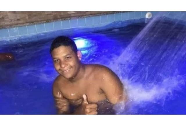 Adolescente moreno, sorrindo, dentro de uma piscina