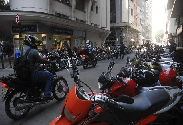 Motoqueiros passam em via com inúmeras motos estacionadas de ambos os lados (Tânia Rêgo/Agência Brasil)