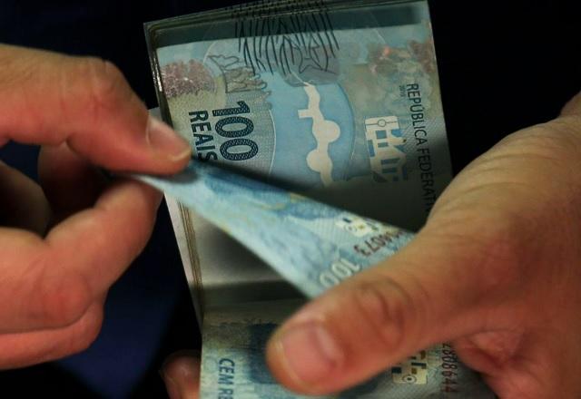 Pessoa manuseia cédulas de R$ 100,00 (José Cruz/Agência Brasil)
