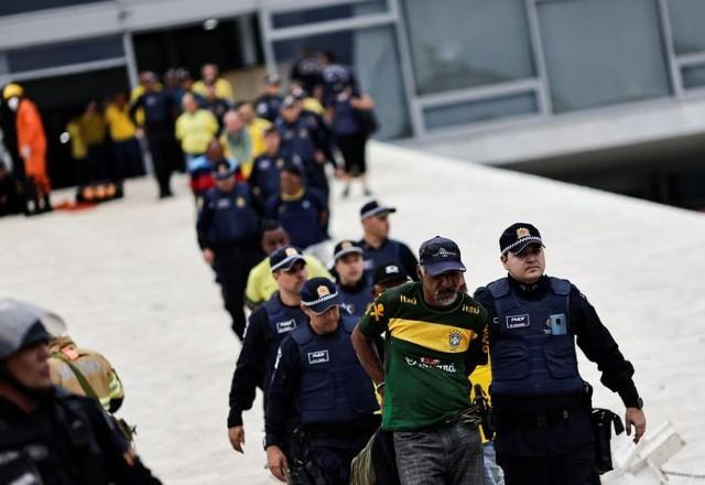 Policiais conduzindo golpistas (Reprodução/Agência Brasil)