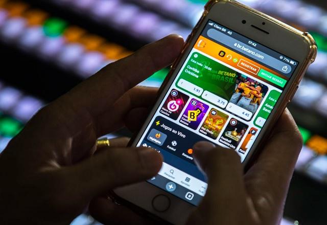 Pessoa segura celular com o site Betano aberto (Joédson Alves/Agência Brasil)