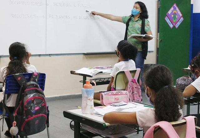 Professora aponta, com canetão, conteúdo escrito em lousa, durante aula para crianças (Rovena Rosa/Agência Brasil)