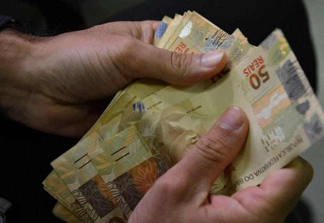 Pessoa segura cédulas de R$ 50,00 (Marcello Casal Jr./Agência Brasil)
