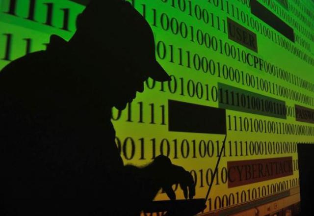 Sombra de homem mexendo em laptop aparece sobre imagem de sequências de números 0 e 1 (Marcello Casal Jr./Agência Brasil)