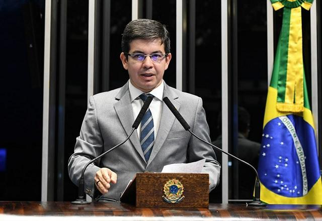 Randolfe Rodrigues fala ao microfone, próximo a bandeira do Brasil (Jefferson Rudy/Agência Senado)