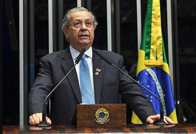Senador Jayme Campos fala ao microfone, à frente da bandeira do Brasil (Jefferson Rudy/Agência Senado)