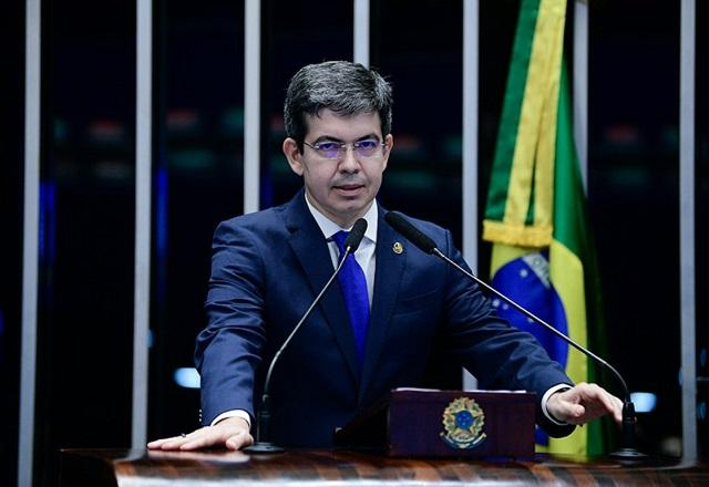 Randolfe Rodrigues fala ao microfone, próximo a bandeira do Brasil (Pedro França/Agência Senado)