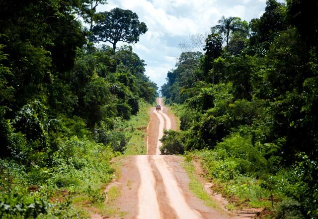Amazônia; na imagem, uma estrada de terra corta a floresta; um carro passa por ela