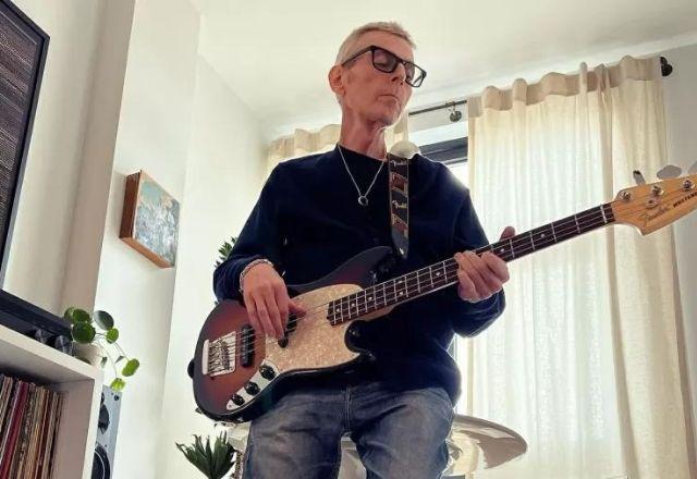 Andy Rourke tocando baixo em meio a sala