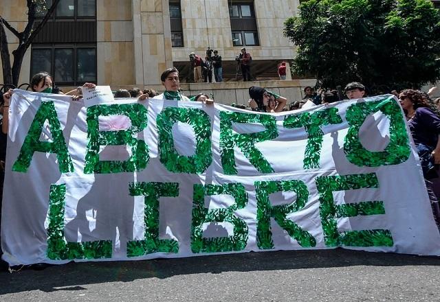 Manifestantes seguram pano com a escrita 'aborto libre' estampada (Reprodução/Anistia Internacional)