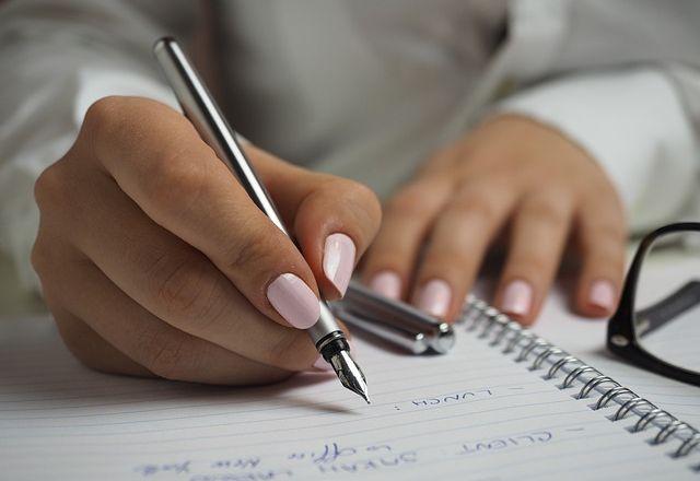 As mãos de uma mulher estão em cima de um caderno