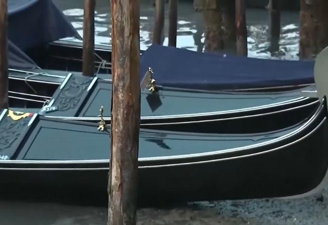 Barco preto em uma parte sobre a água e, em outra, sobre terra úmida