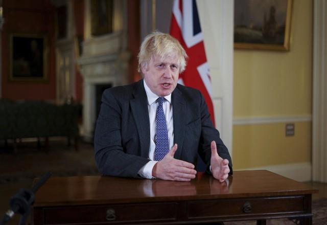 Boris Johnson sentado em seu gabinete usando terno