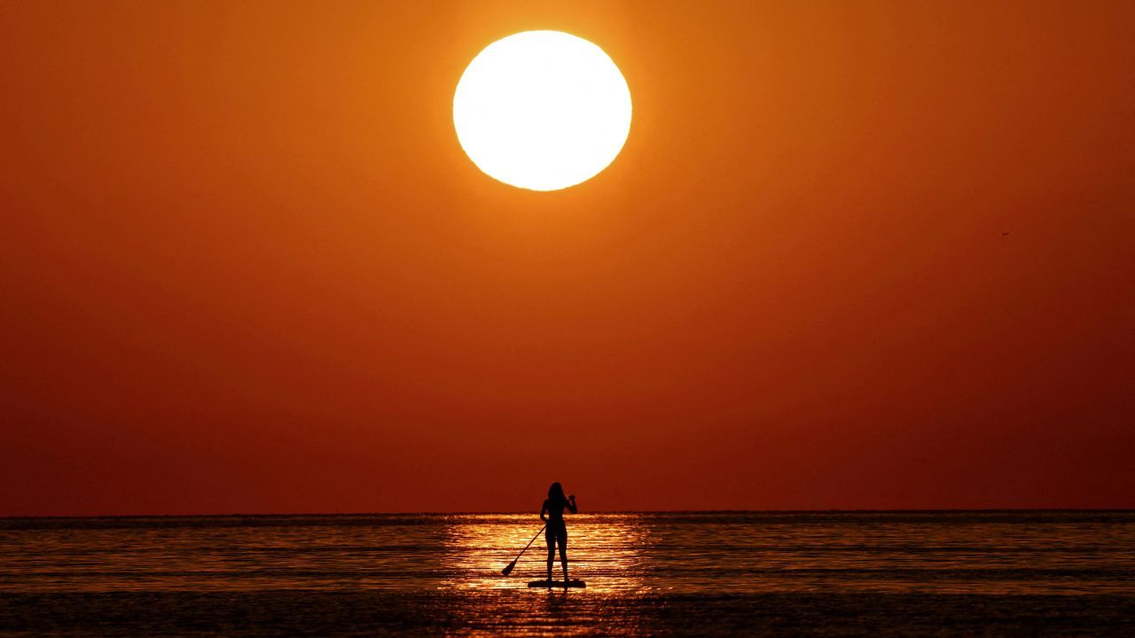Mulher pratica stand-up paddle durante o nascer do sol no Mar Mediterrâneo, em Barcelona, Espanha | Nacho Doce/Reuters