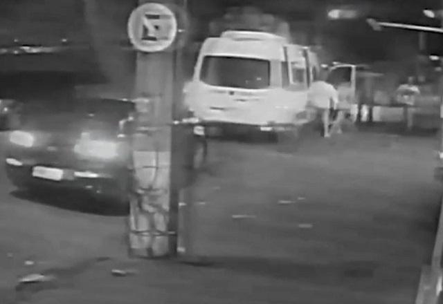 Câmera de segurança mostra carro escuro e van branca durante ataque de criminosos em rua, durante a noite