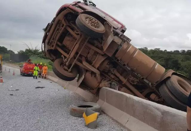 Carreta vermelha pendurada pela cabine em viaduto