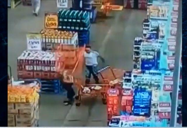 Carrinho de supermercado após ser arremessado por homem de branco quase atingindo uma mulher ao lado