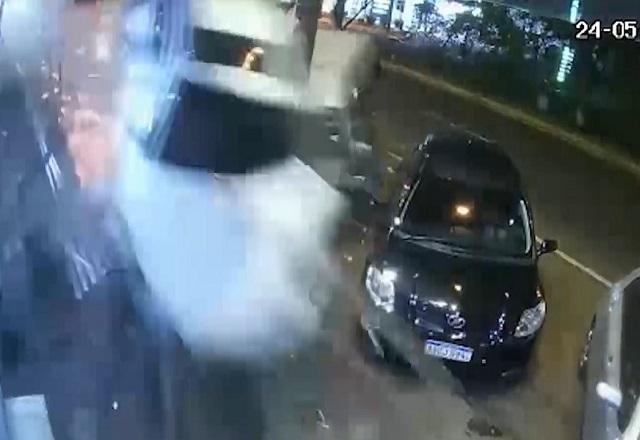 Carro branco voando sobre outros automóveis durante disputa de racha em avenida durante a noite