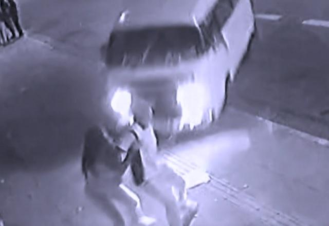 Carro do tipo kombi antes de atingir casal caminhando em calçada