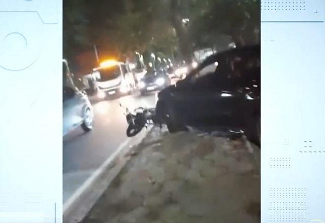 Carro preto de luxo passando por cima de moto em canteiro central de avenida, durante a noite