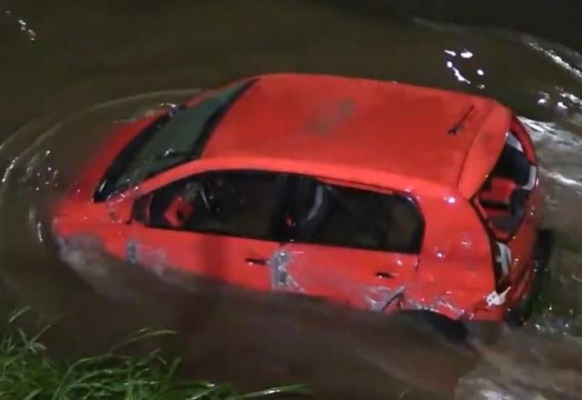 Carro vermelho após acidente, dentro de rio, durante a noite