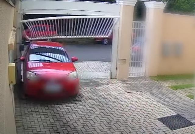 Carro vermelho colidindo contra portão