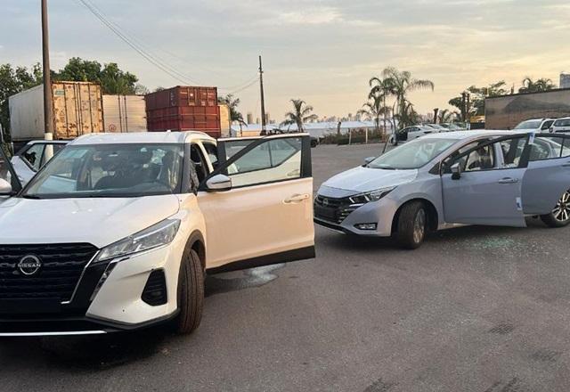 Carros estacionados com vidros destruídos e com marcas de tiros