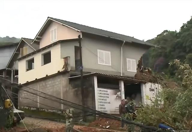 Casa em alto de morro parcialmente destruída ao meio após chuvas e deslizamento