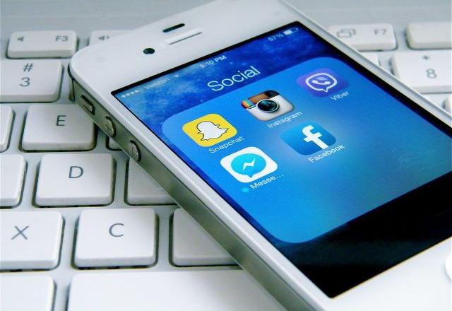 Celular com aplicativos de redes sociais em cima de notebook