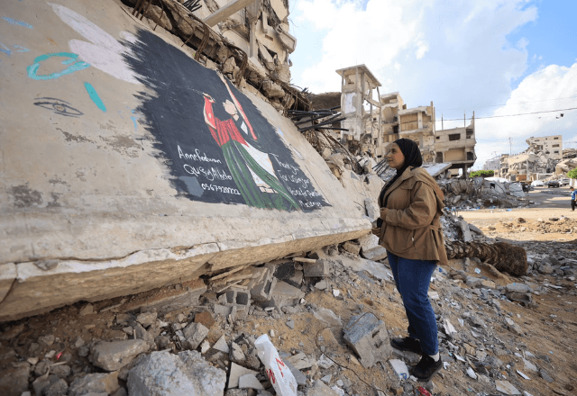 Artista palestina Anne Redwan em frente ao mural que pintou em homenagem ao rapper Macklemore, sobre os escombros na Cidade de Gaza | Foto: Arquivo pessoal