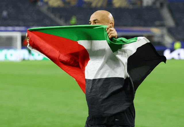 Técnico do Egito, Hossam Hassan, comemora com uma bandeira palestina após a partida em que o Egito se classificou para as oitavas de final da Copa do Mundo | Foto: Hannah Mckay/Reuters - 03.07.2026