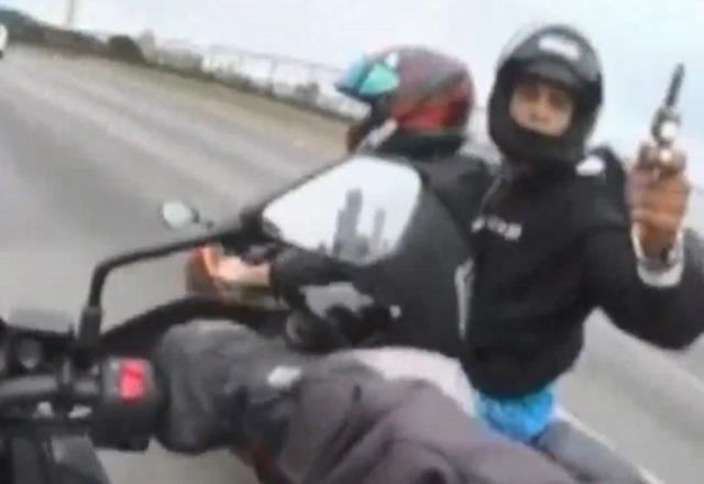 Criminosos em moto, um deles armado, emparelhando com outra moto no meio de rodovia, durante perseguição e tentativa de roubo