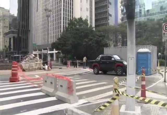 Cruzamento de vias com faixas e cones de interdição, durante o trânsito, ao dia