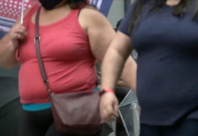 Duas pessoas com roupas escuras, com sobrepeso ou obesidade, caminhando na rua, com foto mostrando apenas o tórax