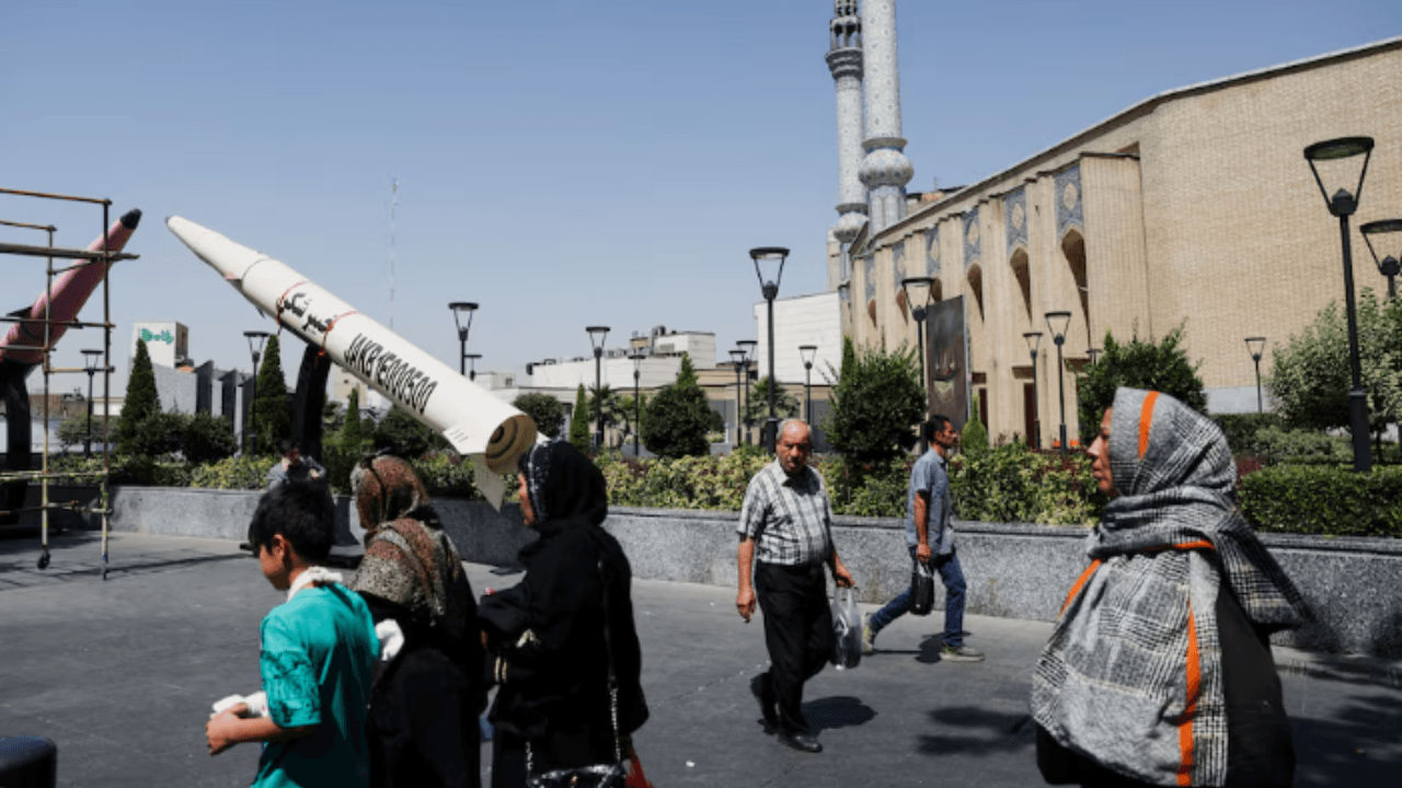 Pessoas caminham ao lado de uma réplica simbólica de um míssil iraniano, em rua de Teerã | Majid Asgaripour/Wana via Reuters