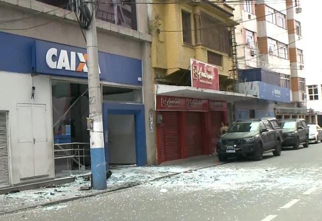 Fachada de agência bancária da Caixa Econômica com vidros estilhaçados na rua após explosão