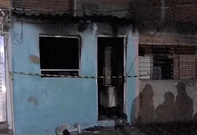 Fachada de casa, na cor azul, com marcas escuras de fumaça após incêndio