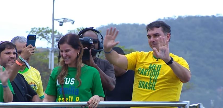 Fernanda e Flávio Bolsonaro acenam para apoiadores no ato inaugural da campanha do candidato do PL à Presidência | Reprodução/YouTube