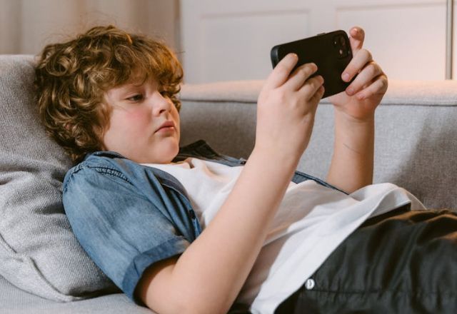Menino assistindo vídeo no celular | Pexels