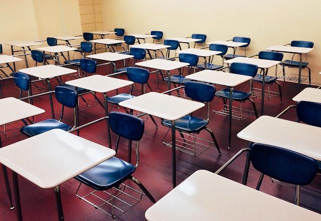 Foto de uma sala de aula cheia de carteiras escolares
