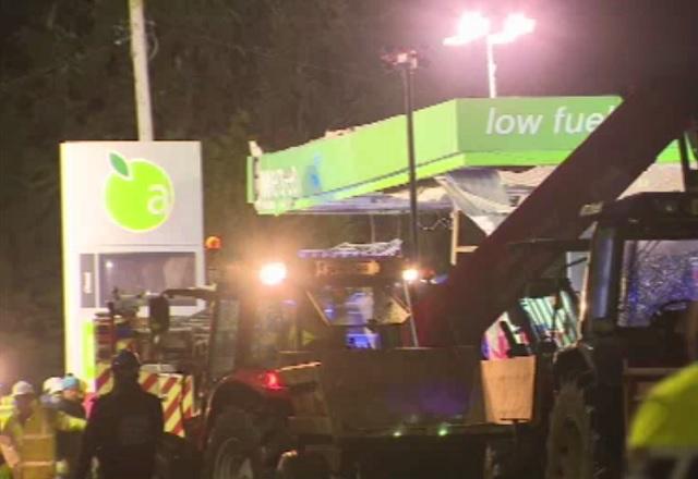 Frente de posto de combustíveis com o teto destruído, durante a noite