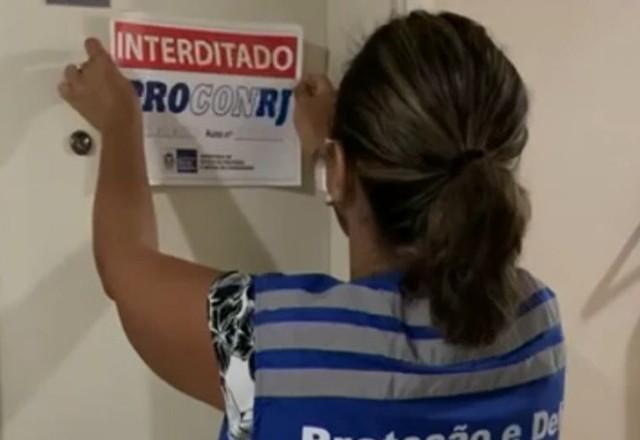 Funcionária do PROCON colando aviso de interditado em clínica estética