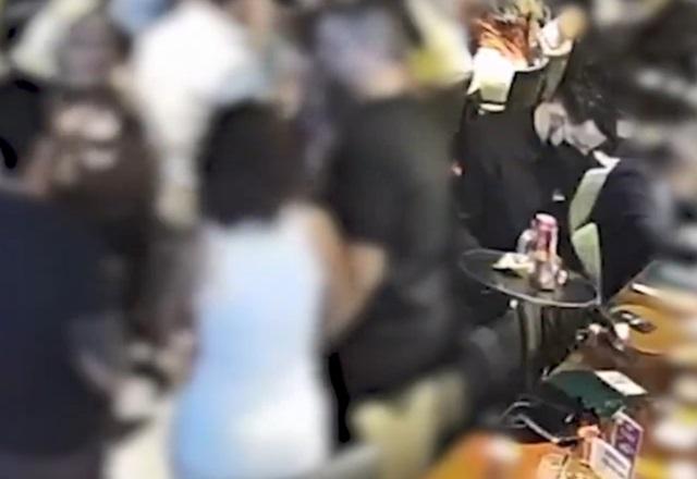 Garçom segurando bandeja ao lado de mesa, retirando itens