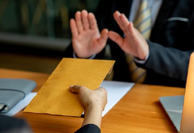 Pessoa recusa envelope que outra lhe oferece (David Gyung/Getty Images)