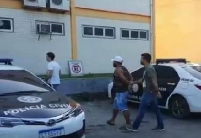 Homem algemado sendo acompanhado por dois policiais