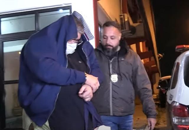 Homem algemado sendo preso pela polícia