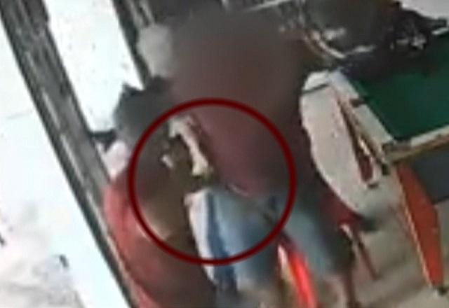 Homem armado roubando arma de bolso de vítima dentro de bar, perto de mesa de sinuca