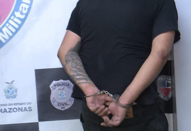 Homem branco com tatuagem no braço, de costas e algemado