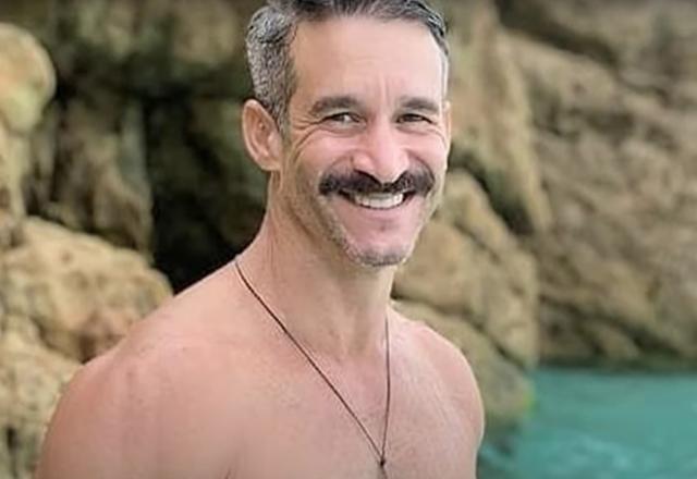 Homem branco de olhos claros e bigode sorrindo